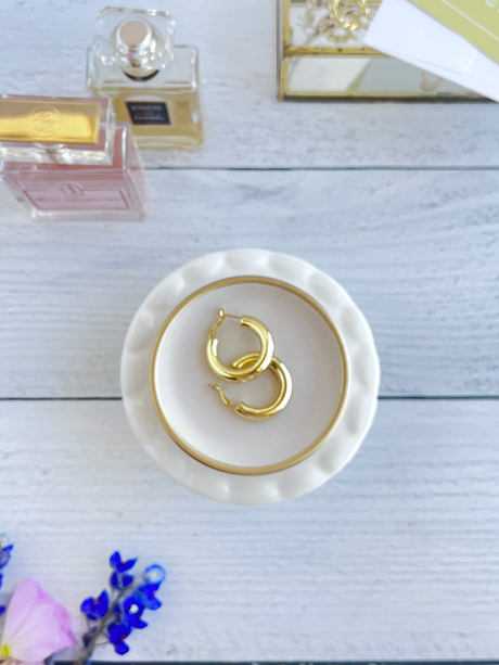 a photo of a person putting earrings in a jewelry dish in a luxury basthroom