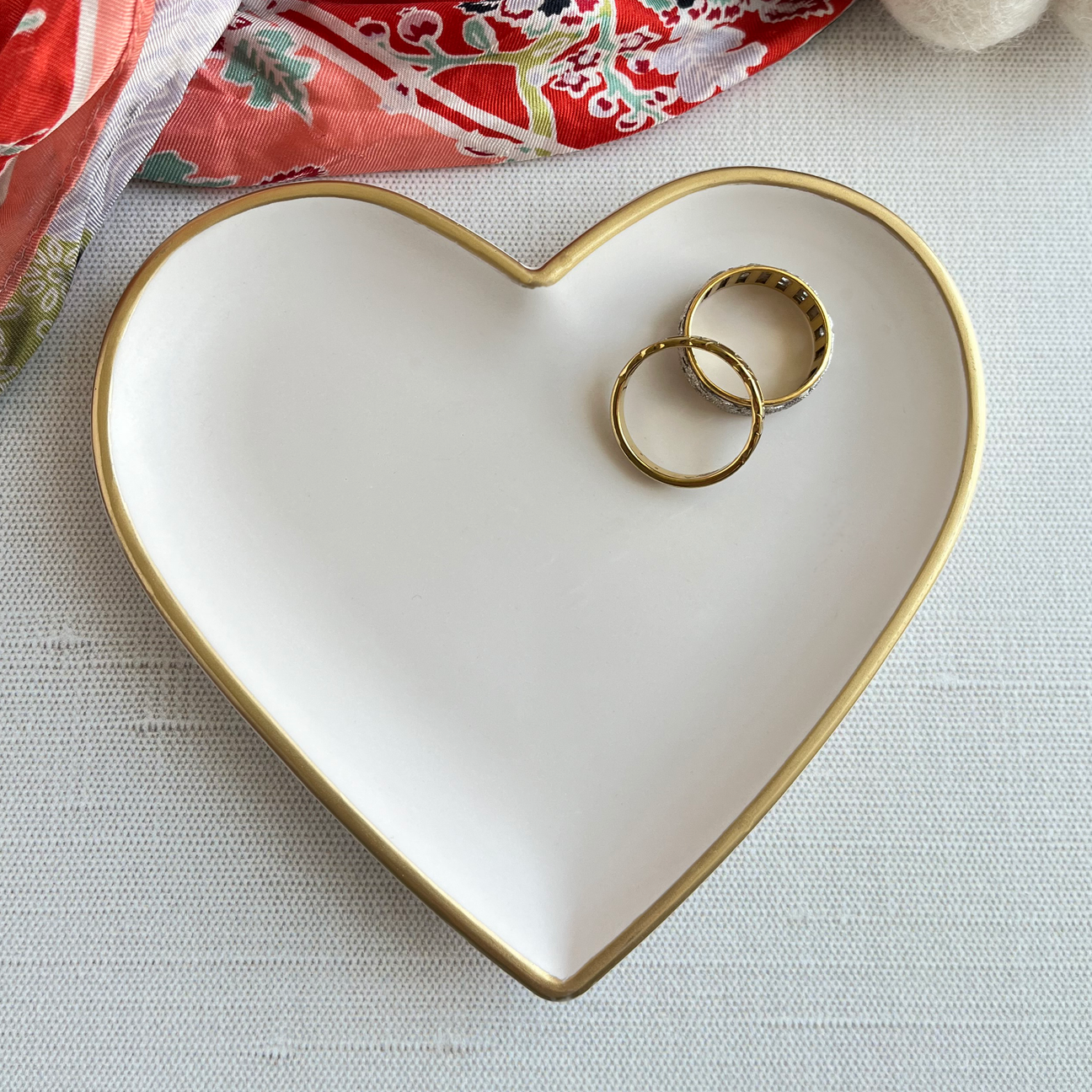 cream colored heart shaped dish with jewelry on it